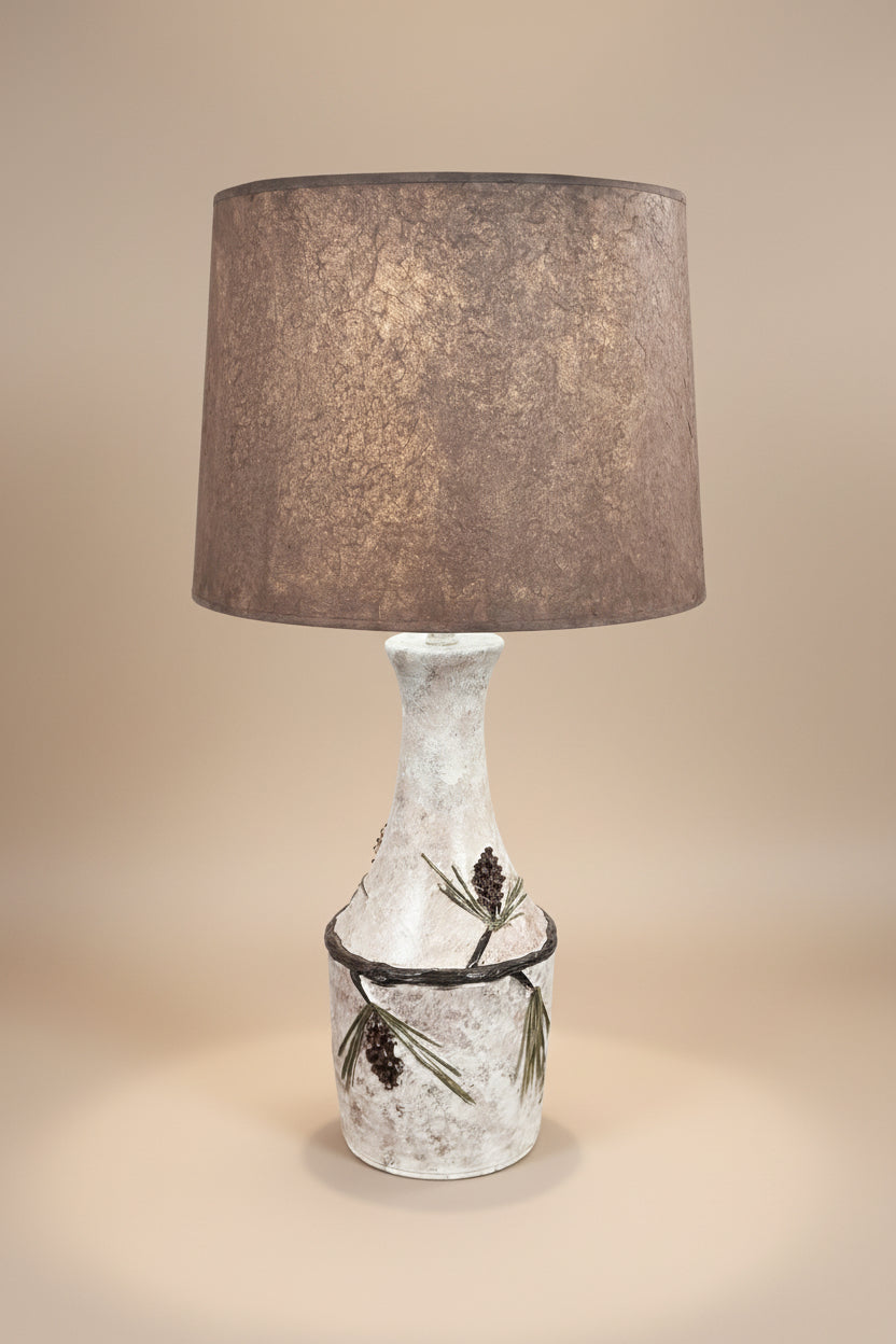Decorative table lamp with textured brown shade and decorative base on a white background