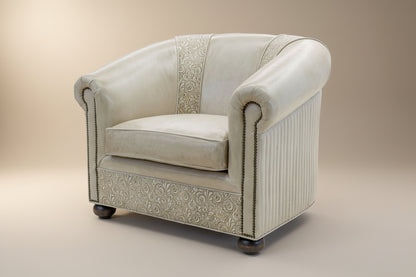 An ivory leather chair with hand-tooled details and turned bun feet, featuring brass studs.