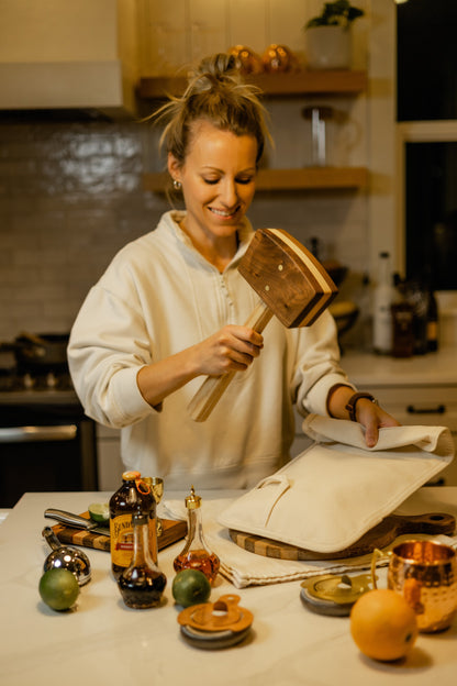 Diamond W Ranch black walnut ice mallet held by a woman preparing cocktails in a kitchen