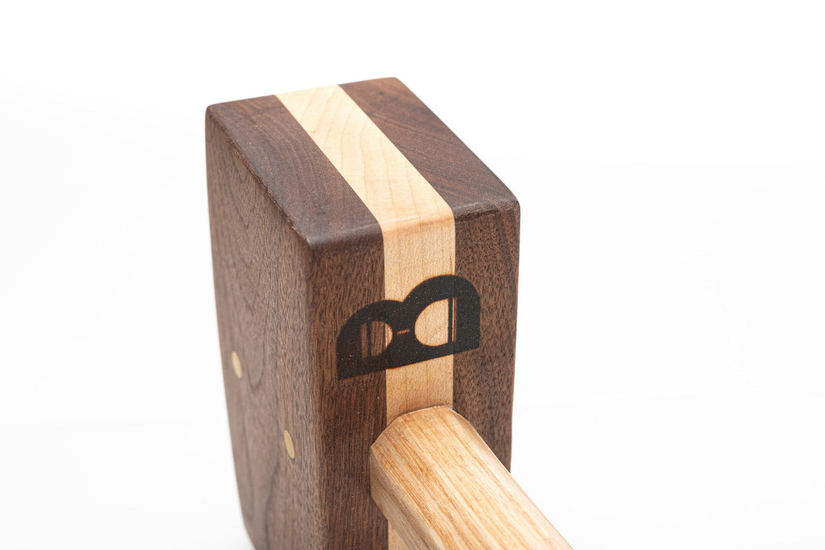 Diamond W Ranch black walnut ice mallet head close-up showing the maple stripe and B logo on white