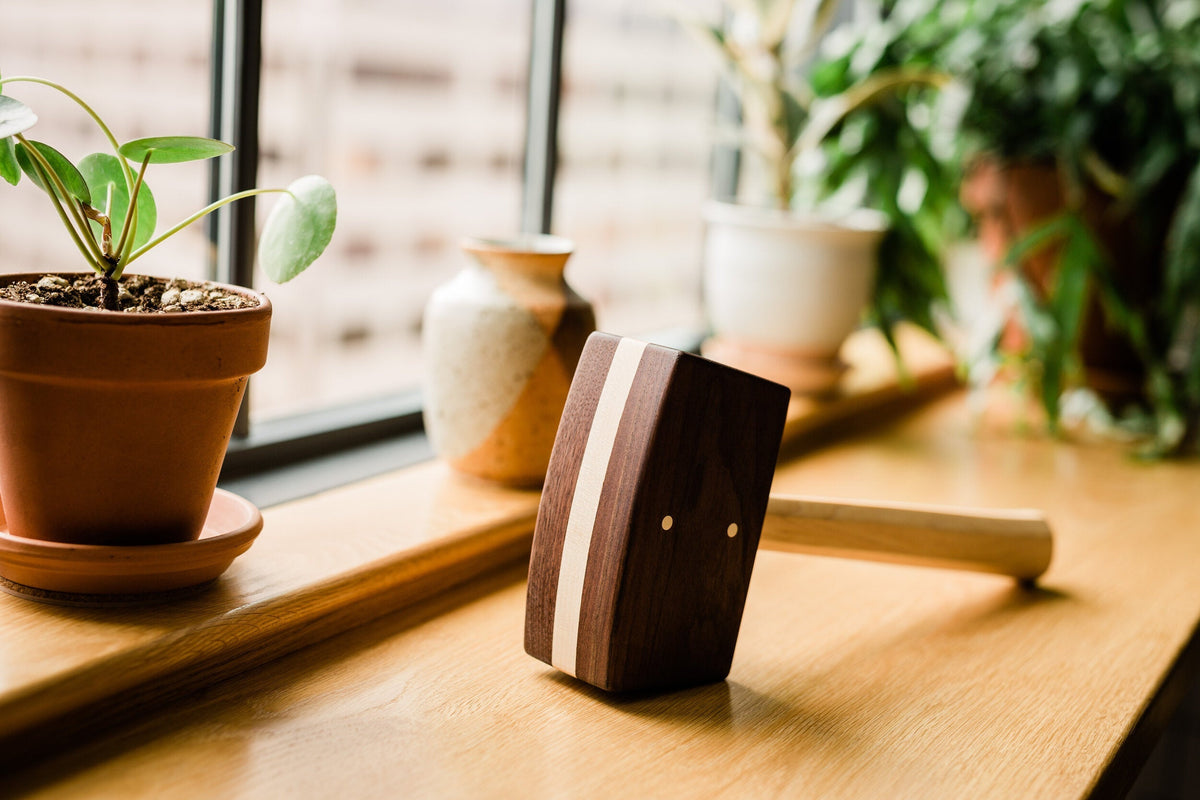 Diamond W Ranch black walnut ice mallet lying on a wood table by a sunny window with potted plants