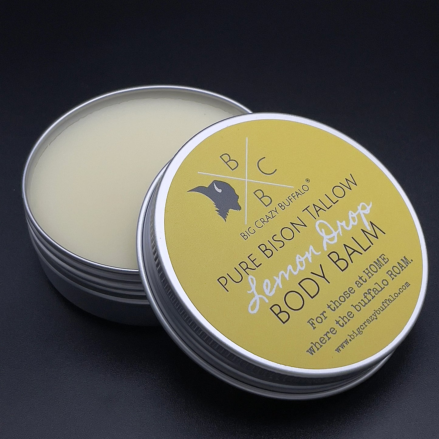 open can of lemon drop body balm with a black background